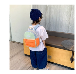 Kids color-block backpack with adjustable straps shown on a model for size perspective