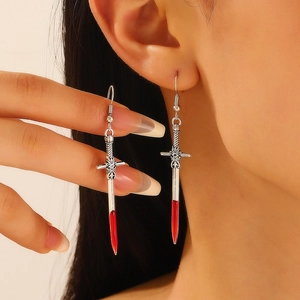 Gothic silver sword earring with red translucent tip held by hand in close-up detail