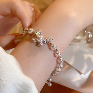 Dettaglio ravvicinato di un elegante braccialetto di perle a farfalla con cristalli micro-pave.