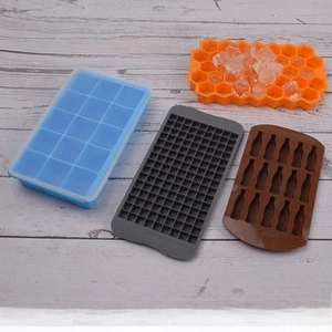 Flat lay of colorful silicone ice cube trays in honeycomb and bottle shapes on wood