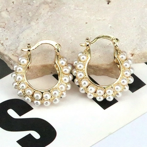Detailed shot of gold-plated hoop earrings with double-row inlaid white pearls on a stone