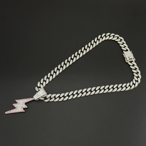 Close-up of a silver Cuban chain necklace with a pink lightning bolt pendant and rhinestones