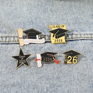 Class of 2026 graduation enamel pins set on denim fabric featuring mortarboard designs