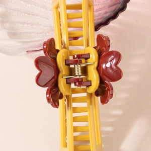 Dettaglio macro della pinza per capelli giallo zenzero con decorazioni floreali rosso scuro