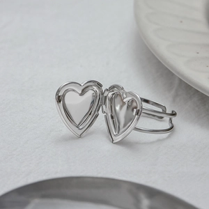 Anello con medaglione a cuore in acciaio inossidabile argento su sfondo bianco minimale