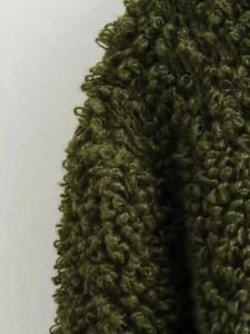 Detailopname van mosgroene krullende fleece stoftextuur voor winterse gebreide vesten