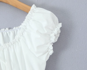 Detail of white square neck blouse featuring ruffled edges and puff sleeve texture