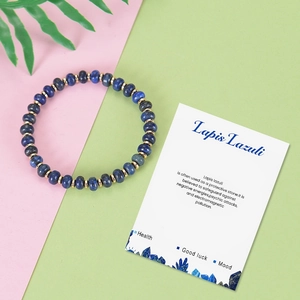 Lapis Lazuli beaded bracelet with gold spacers and meaning card on colorful background
