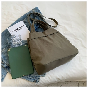 Army green lightweight nylon tote bag shown in a stylish minimalist lifestyle setting