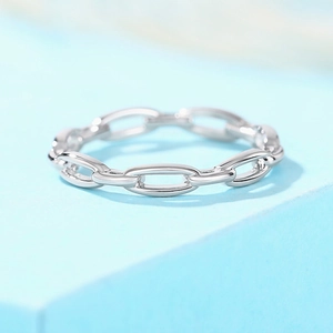Détail de la bague polie à maillons argentés sur un support géométrique bleu clair