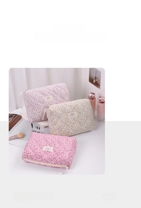 Detailed close-up of quilted floral makeup bags in soft pink, yellow, and cream cotton fabric