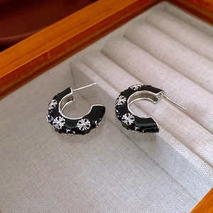 Close-up of vintage black enamel C-shaped floral earrings in a jewelry box
