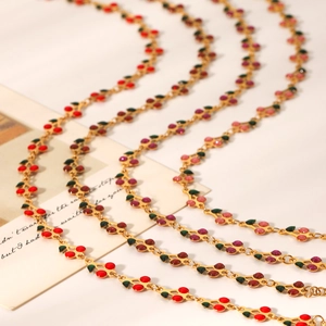 Detail view of four gold cherry necklaces with red and pink enamel pendants on white background