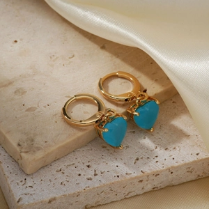 Elegant gold-plated hoop earrings featuring turquoise heart-shaped pendants on stone texture