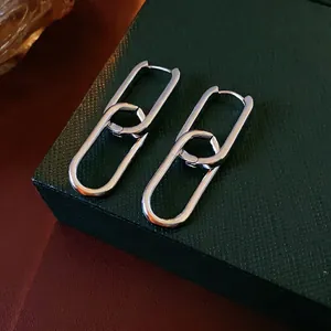Minimalist silver interlocking oval link earrings displayed on a dark luxury jewelry box