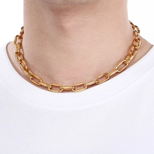 Close-up of golden chunky chain necklace with textured oval links on a model neck