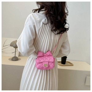 Pink quilted mini crossbody bag with a bow detail worn with a stylish pleated skirt