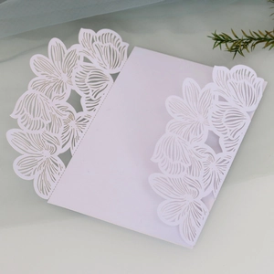 Detail of white laser-cut floral invitation card with intricate hollowed patterns