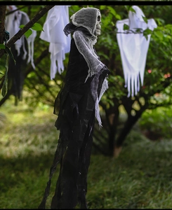 Outdoor Halloween hanging grim reaper and white gauze ghosts on tree branches