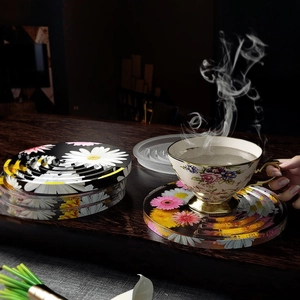 Detailed view of round floral resin coasters with non-slip ridges on a dark wood table