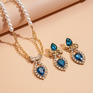 Vintage gold necklace set with pearls, blue water-drop gemstone and crystal bow pendant