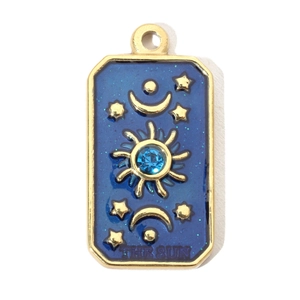 Macro view of sun tarot pendant with blue enamel, gold plating and sparkling blue crystal