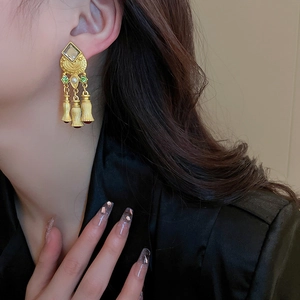 Vintage gold tassel earrings with colorful stones and pearls on a professional model