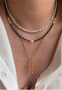 Détail du collier de perles d'eau douce superposé avec perles bleues et croix en or