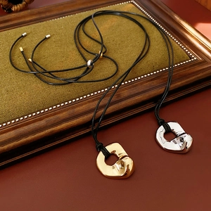 Detailed view of silver and gold irregular metal pendants on black adjustable cords