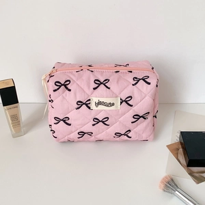 Detail of pink quilted cosmetic bag with black bow patterns and top zipper closure