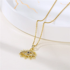 Gold Evil Eye pendant necklace with blue zircon on a white marble background