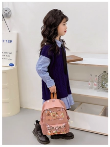 Pink cartoon Capybara backpack for children shown on a model in a cozy home setting