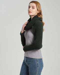 Detail view of dark green knitted scarf with sleeves on a model in a studio setting