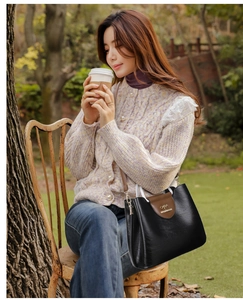 Detail of a chic black PU leather tote with kangaroo logo in a relaxed outdoor park setting