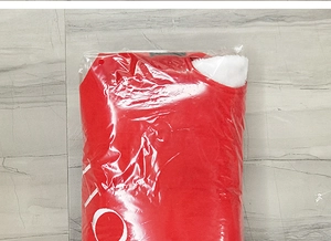 Close-up of a red plaid Christmas tree skirt with white snowflake patterns in packaging