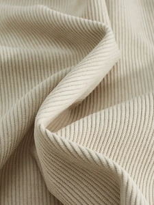 Macro shot of beige corduroy fabric texture showing vertical ridges and soft velvet surface