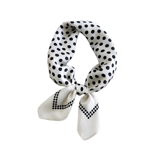 Elegant white silk square scarf with black polka dots tied in a stylish circular knot