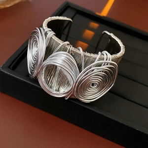 Detailed macro view of silver multilayered wire-wrapped cuff bracelet with triple spirals