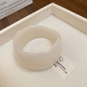 Macro shot of an off-white wavy resin bangle on a soft fabric display tray
