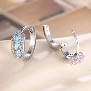 Silver geometric hoop earrings with blue and pink zircon stones on a beige background