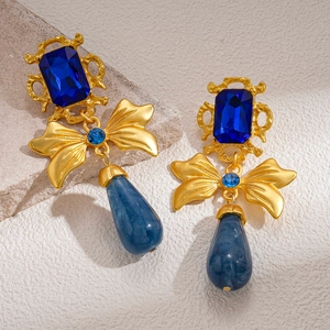 Macro shot of vintage gold earrings with navy blue square gems and teardrop pendants