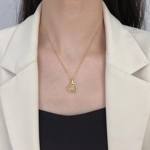 Close-up of golden heart pendant with colorful pavé zircons worn on a model's neck