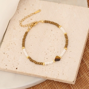 Bohemian beaded bracelet with heart tiger eye stone pendant on a textured background
