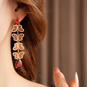 Gros plan de boucles d'oreilles papillon vintage avec zircon rouge et franges dorées