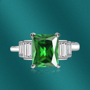 Macro view of emerald-cut green gemstone ring with side baguette zircons in silver