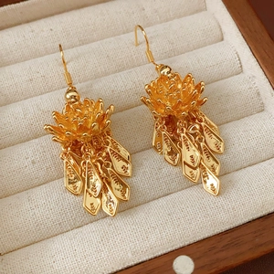 Macro shot of gold-plated lotus flower earrings with leaf tassels in a linen jewelry box
