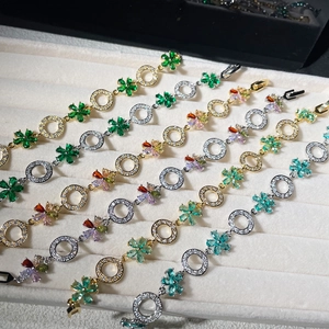 Detail of flower zircon bracelets in gold and silver finish on velvet tray