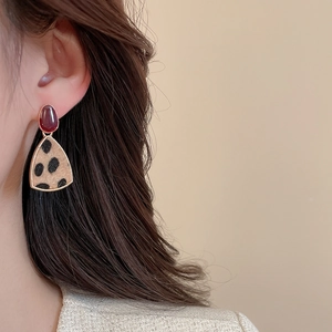 Close-up of leopard print triangle earrings with burgundy stud on model for vintage look