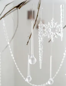 Transparent acrylic Christmas ornaments with icicles and snowflakes on dry branches
