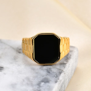 Macro view of golden stainless steel signet ring with black inlay and checkered band